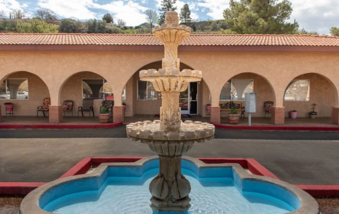 A decorative fountain situated in a courtyard with archways and a tiled roof.