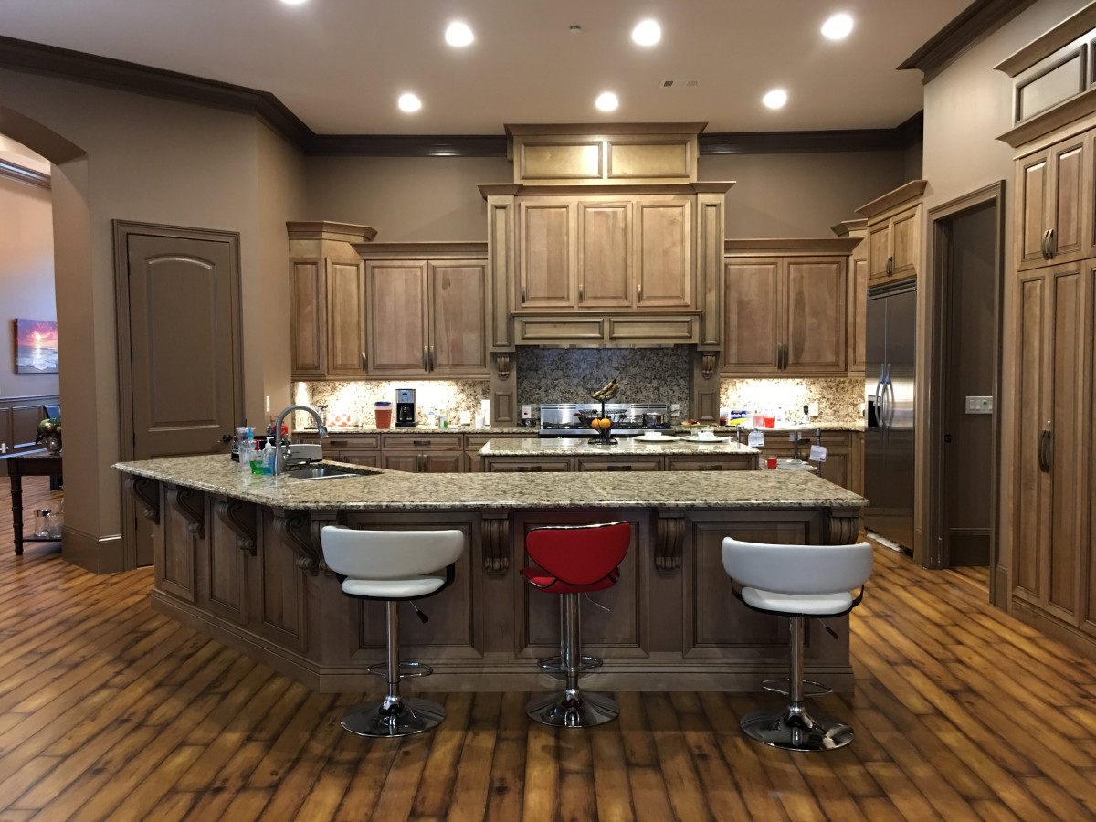 A modern kitchen with wooden cabinets, a granite countertop island, and bar stools.