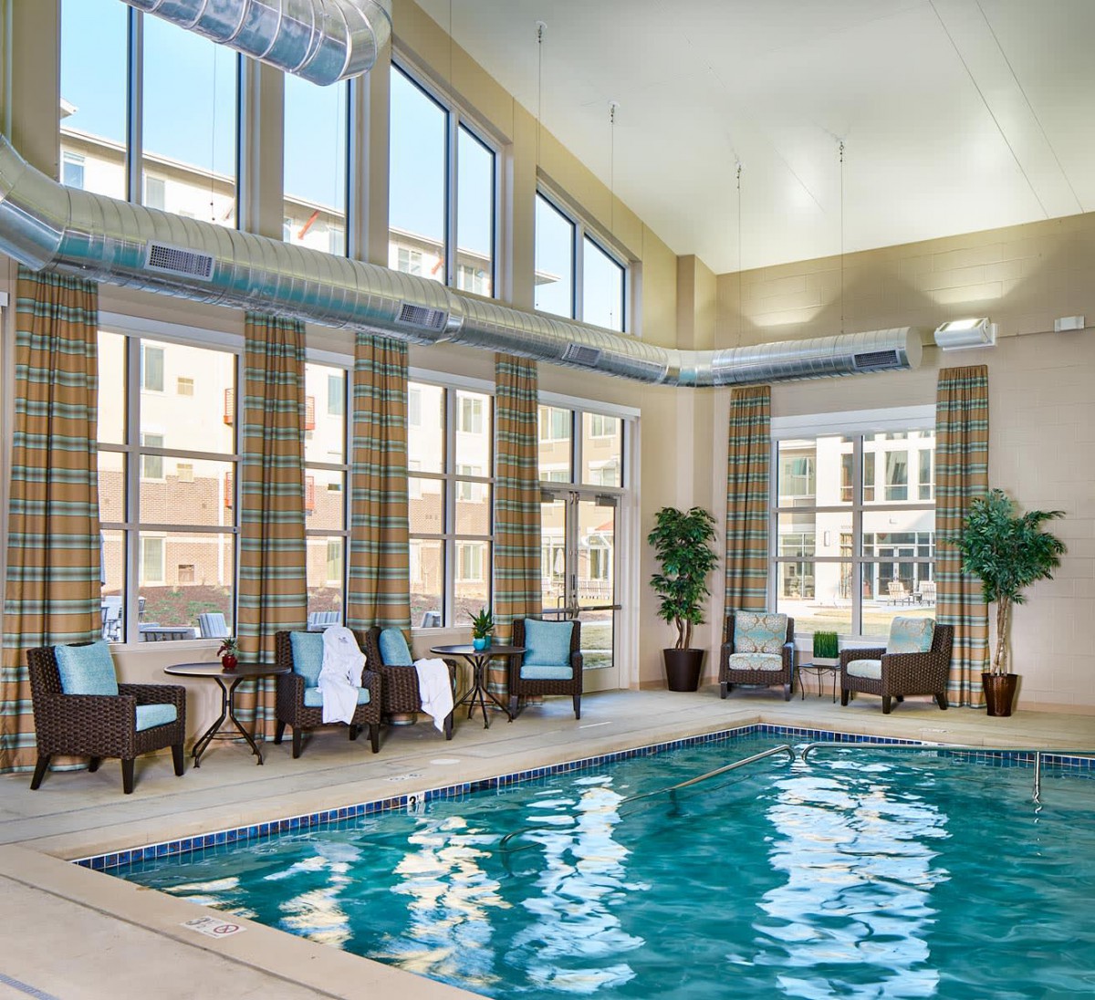A luxurious indoor swimming pool with ample seating and natural light streaming through large windows.