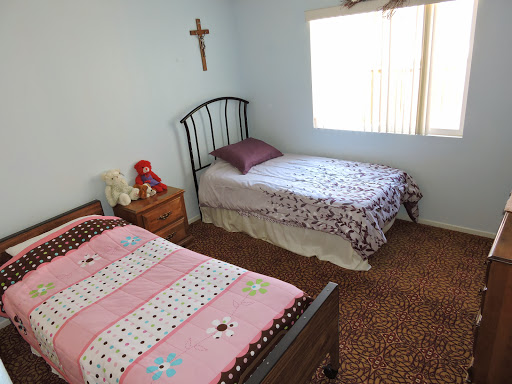 A cozy children's bedroom featuring two beds, decorated with playful bedding, and a cross on the wall.