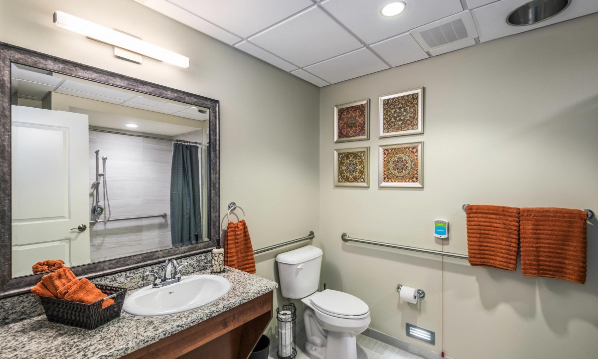 A modern and clean bathroom featuring a sink, toilet, mirror, and wall decor.