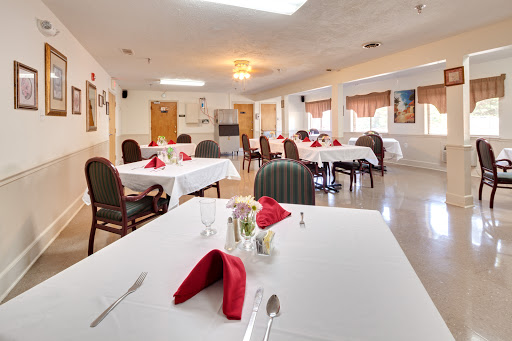 A neatly arranged dining area ready for guests, featuring tables with white tablecloths and red napkins.
