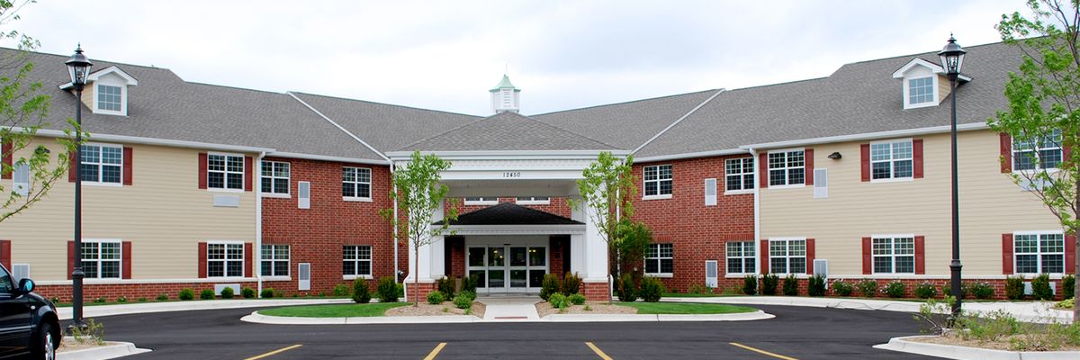 A brick building with a prominent entrance and surrounding greenery.