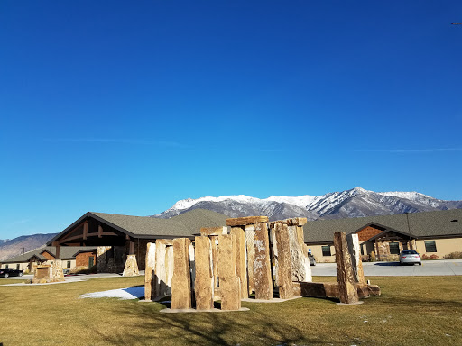 A serene landscape featuring wooden structures in the foreground, with majestic mountains and a clear blue sky in the background.