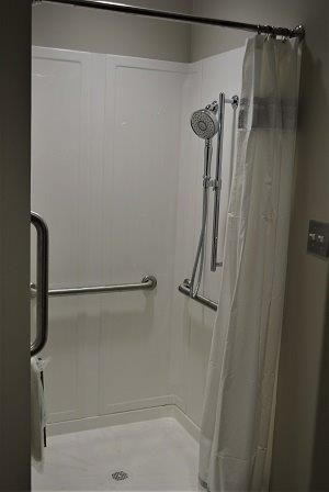 An accessible shower with handrails and a curtain.