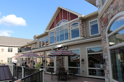 A charming restaurant featuring outdoor seating and large windows, set against a clear blue sky.
