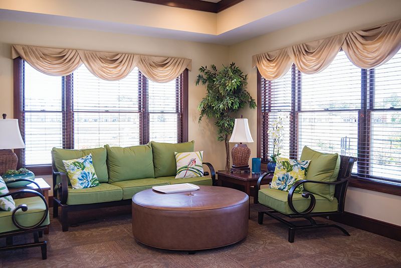 A cozy living room with green furniture and a round brown coffee table.