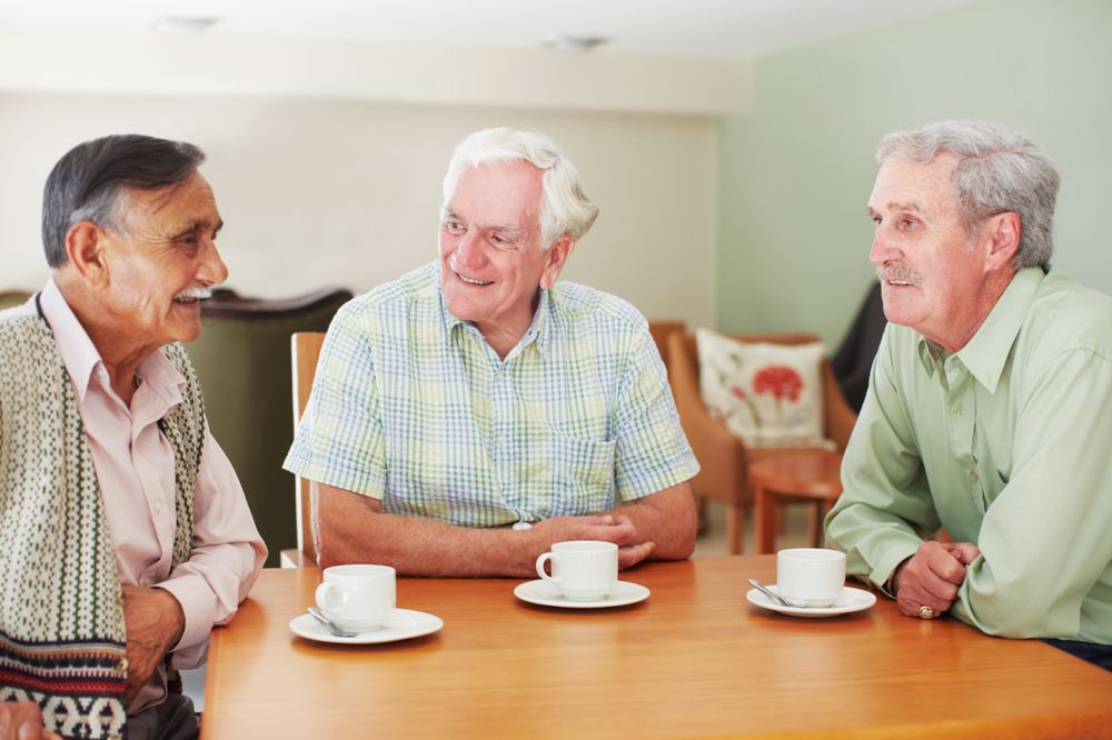 Three elderly men enjoying a conversation over coffee.