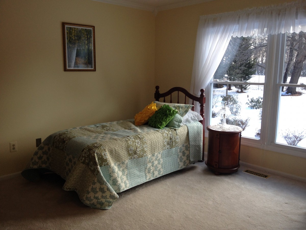 A cozy bedroom with a single bed and a window view.