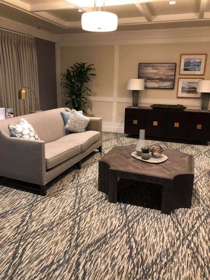 A stylish living room with a grey sofa, modern coffee table, patterned carpet, and decorative elements.