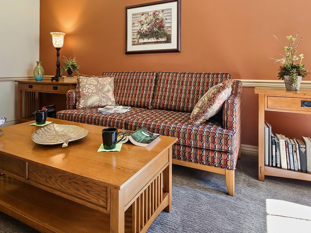 A cozy living room with a patterned sofa, wooden coffee table, and warm lighting.