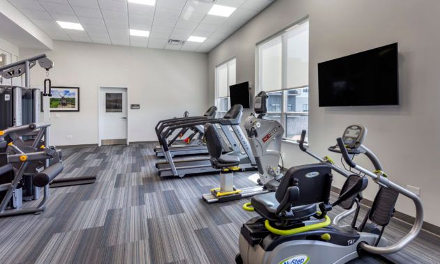 Modern gym interior with exercise equipment including treadmills and stationary bikes.
