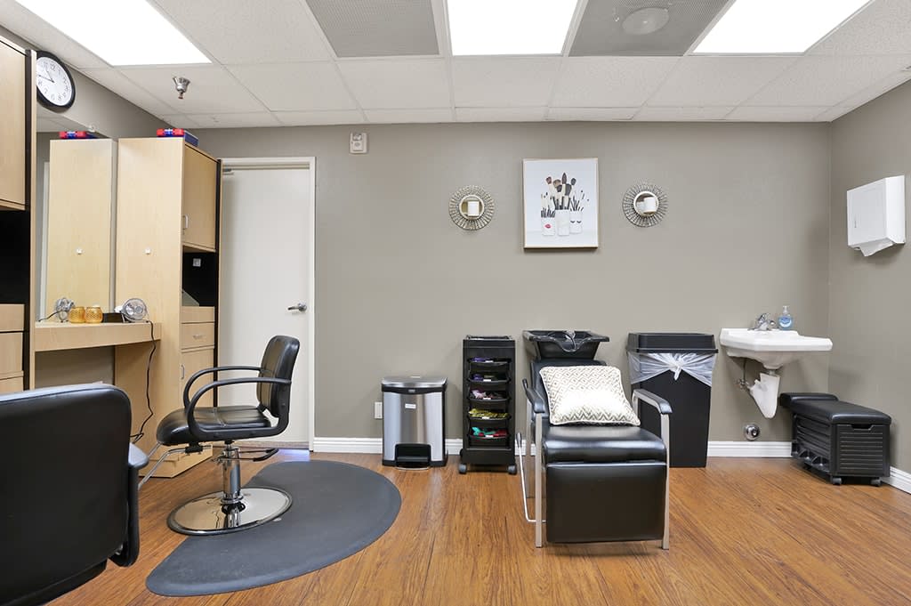 A modern hair salon interior with a styling chair, wash station, and clean decor.