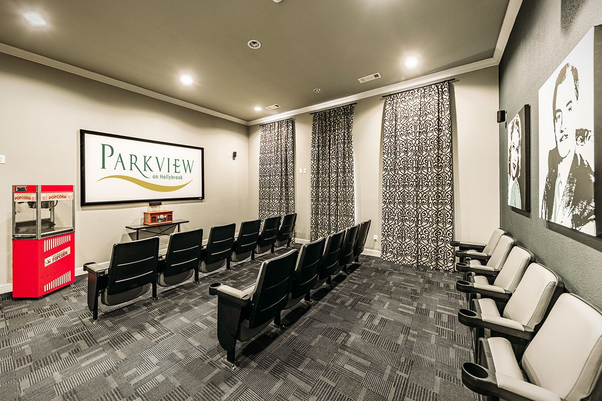 A small theater room with rows of seating facing a projector screen.