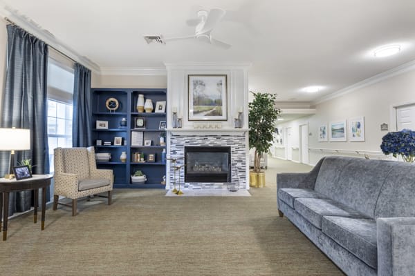A cozy living room featuring a fireplace, bookshelf, sofa, and armchair with elegant interior design.