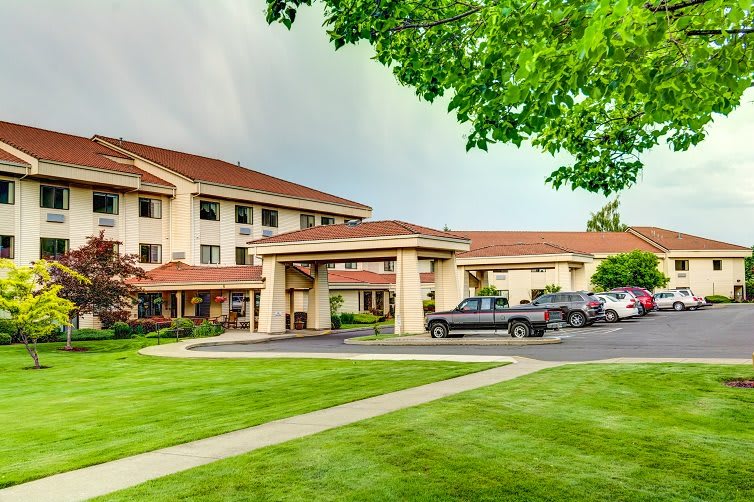 A hotel with a well-maintained exterior, featuring a parking lot and landscaped surroundings.