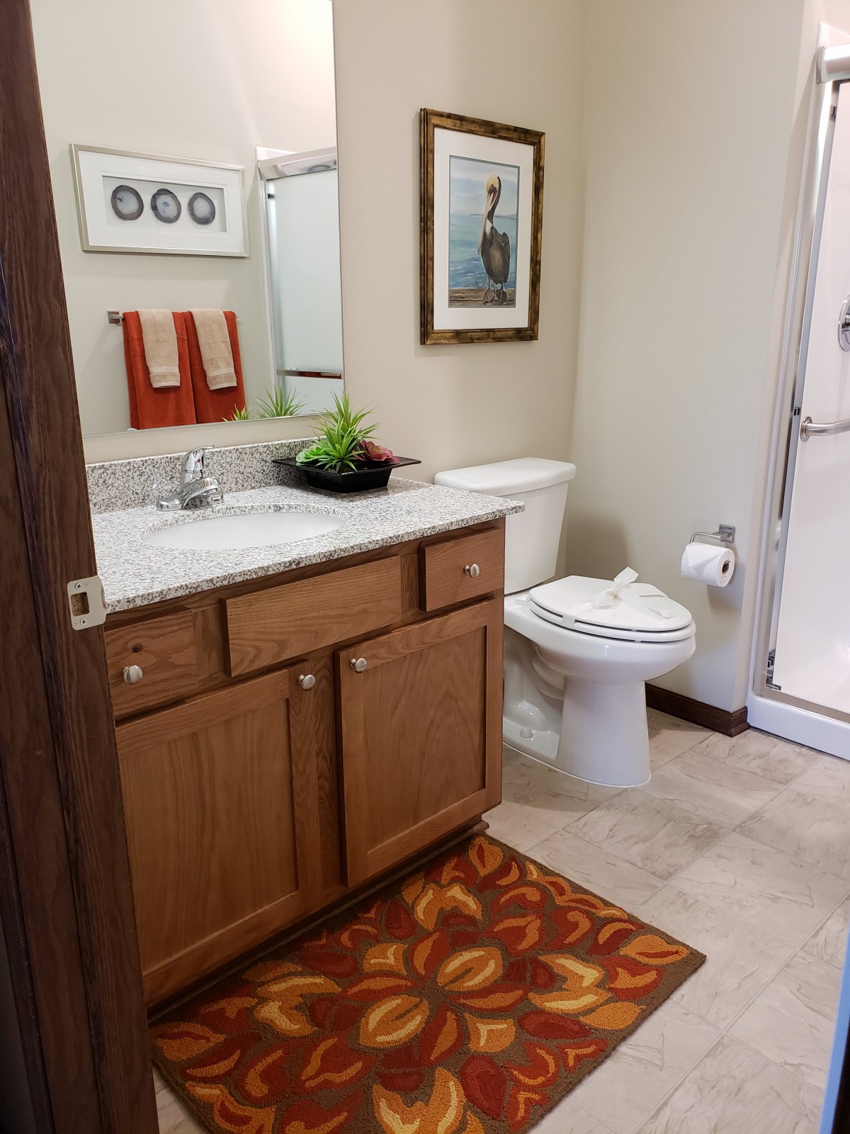 A neatly organized bathroom with a wooden vanity, mirror, toilet, and shower area.