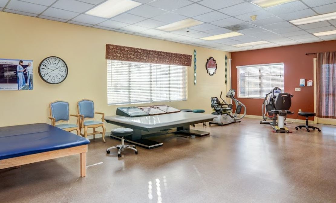 A well-equipped rehabilitation therapy room with exercise equipment and seating areas.