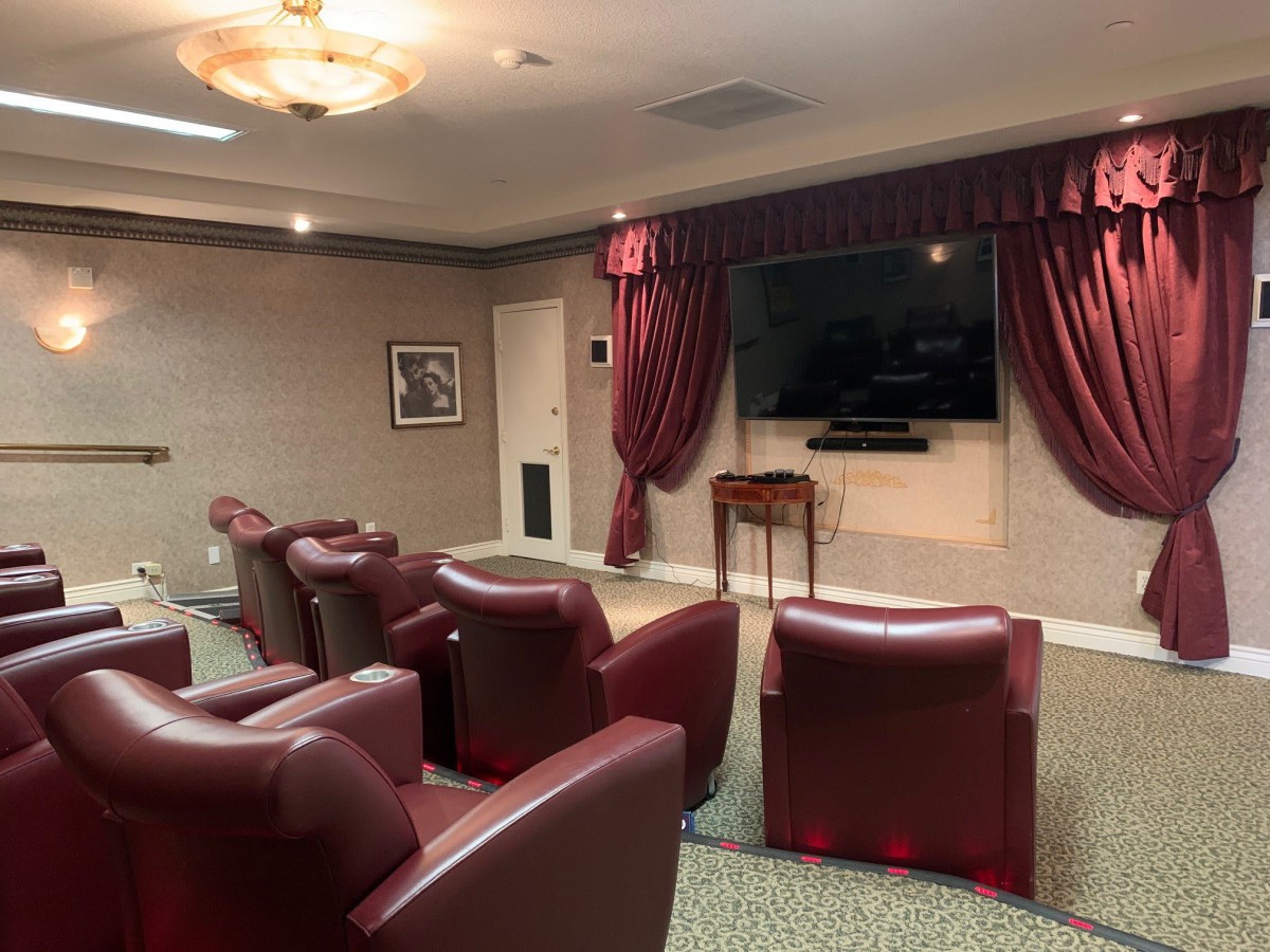 A cozy home theater setup with comfortable armchairs and a large television screen, adorned with red curtains.