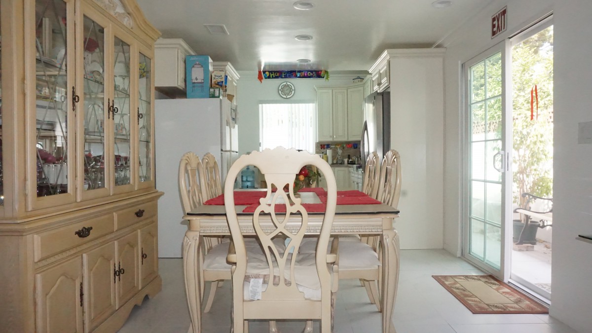 A bright dining area featuring a vintage-style table and chairs, leading into a cozy kitchen space.