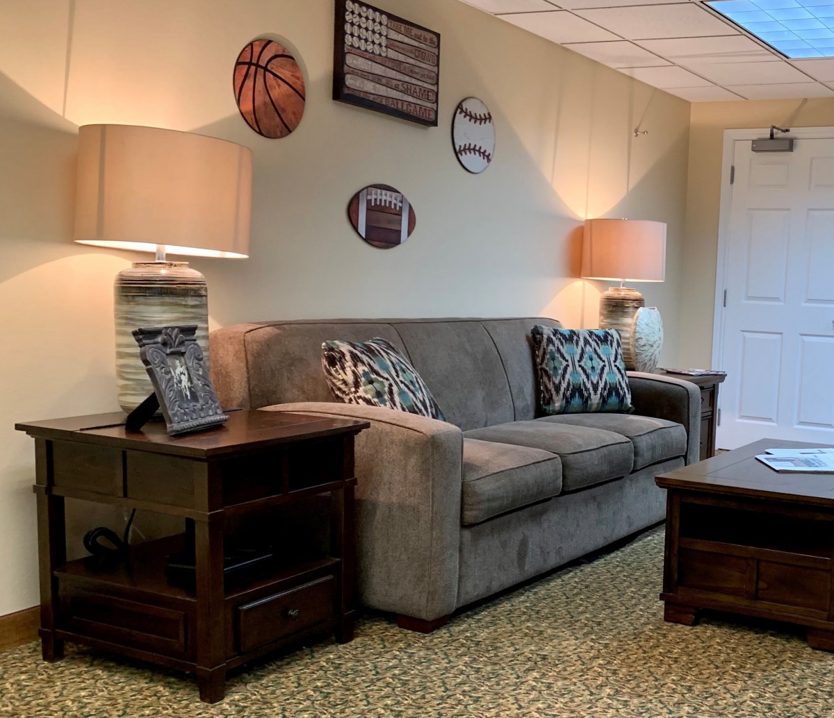 A cozy living room with a sofa, side tables, and sports-themed wall decor.