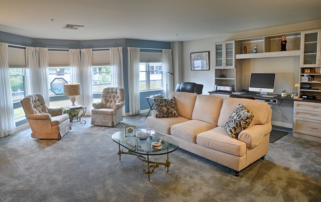 A spacious and elegantly furnished living room featuring a large sofa, armchairs, and a glass coffee table.
