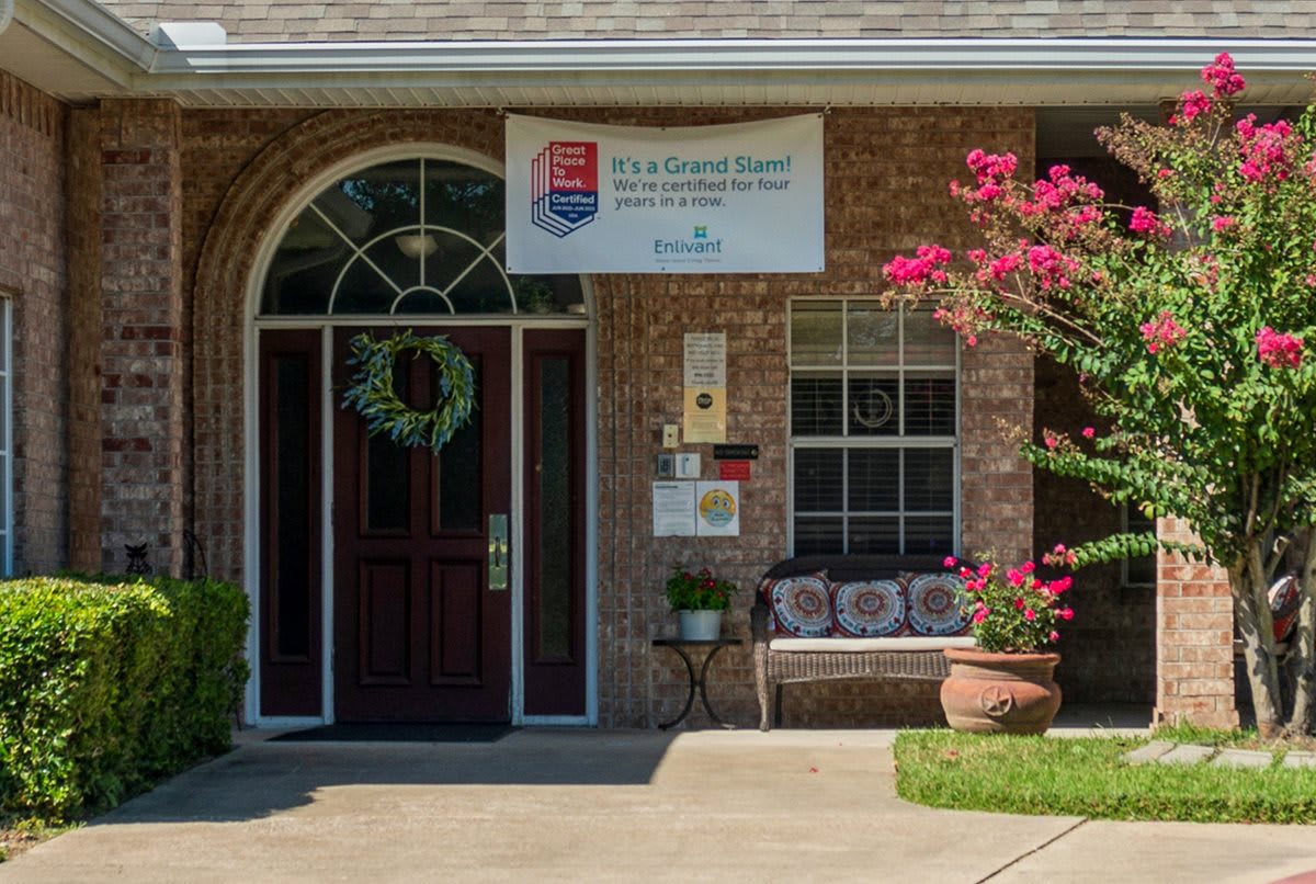 A quaint building entrance with a welcoming bench and vibrant flowers.