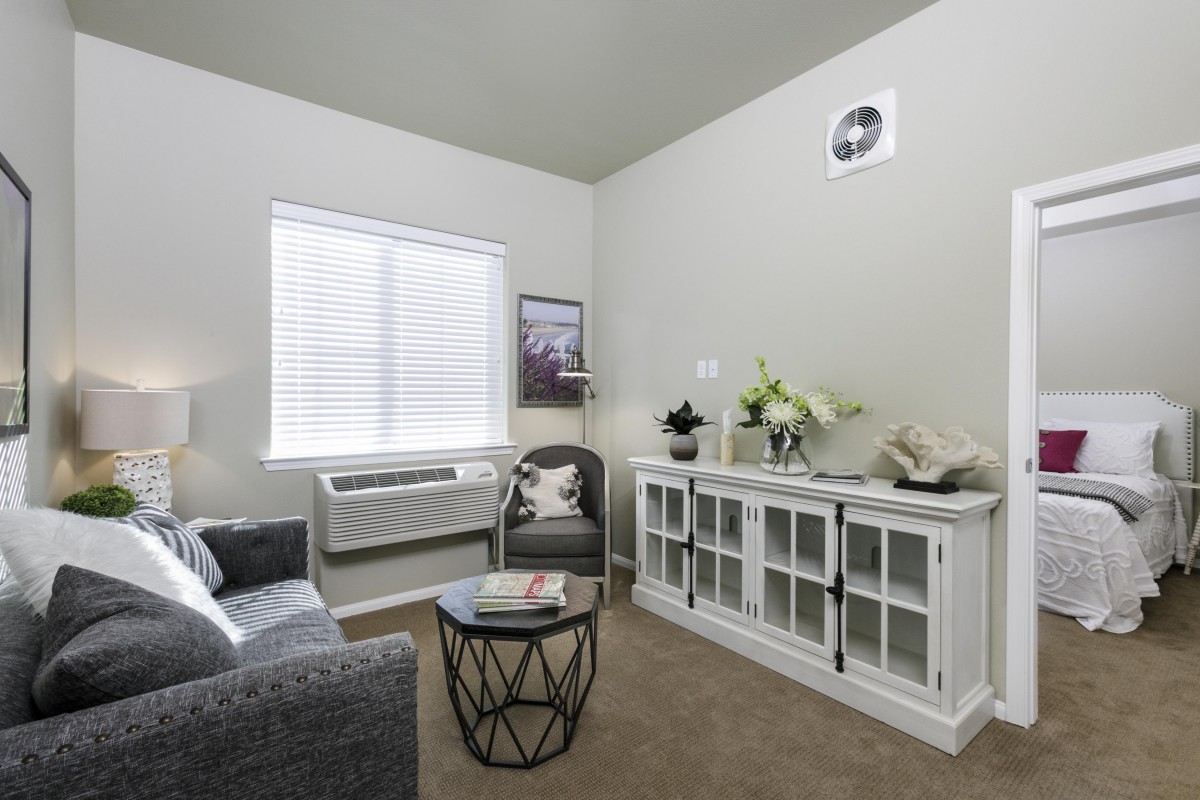 A cozy living room with a modern gray sofa, a geometric coffee table, and a white glass-front cabinet adorned with decor.