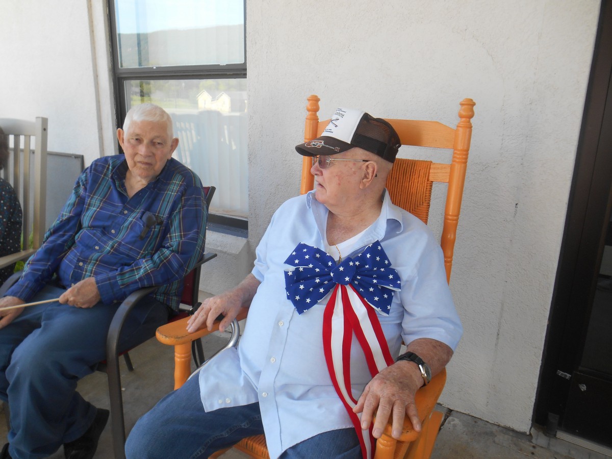 Two elderly men sitting outside, one wearing a patriotic bow tie.