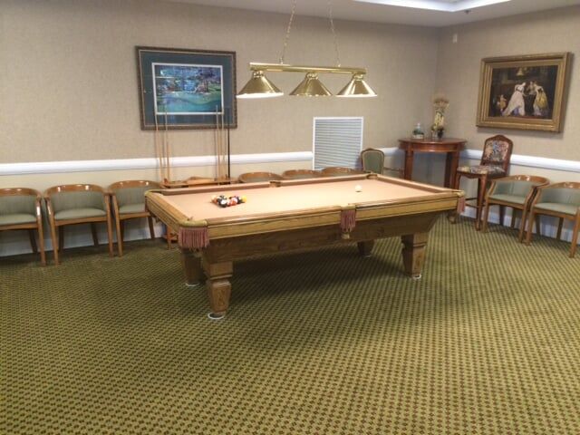 A well-furnished game room featuring a pool table surrounded by chairs and decorated with wall artwork.