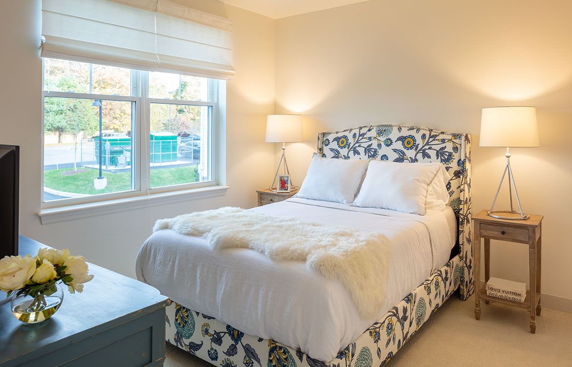 A cozy bedroom with a floral-patterned bed and a soft ambient glow from the lamp.