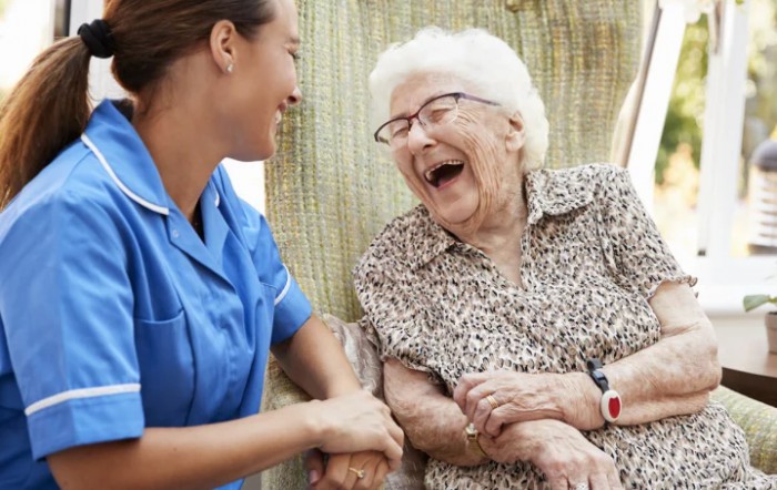 A caregiver sharing a joyful moment with an elderly woman.