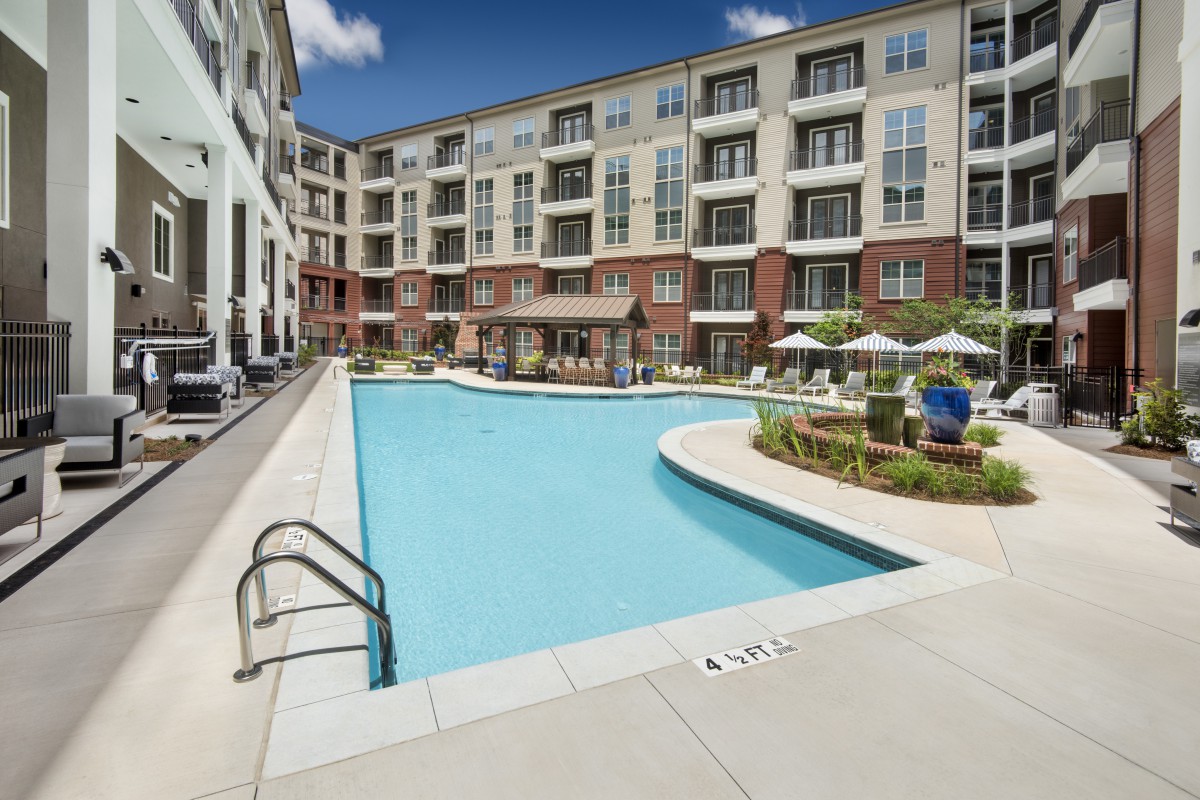 A modern apartment complex with an outdoor swimming pool and patio area.