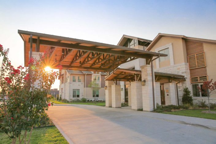 A modern building with a covered driveway during sunset.