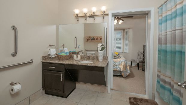 Modern bathroom vanity area with a view into a cozy bedroom.