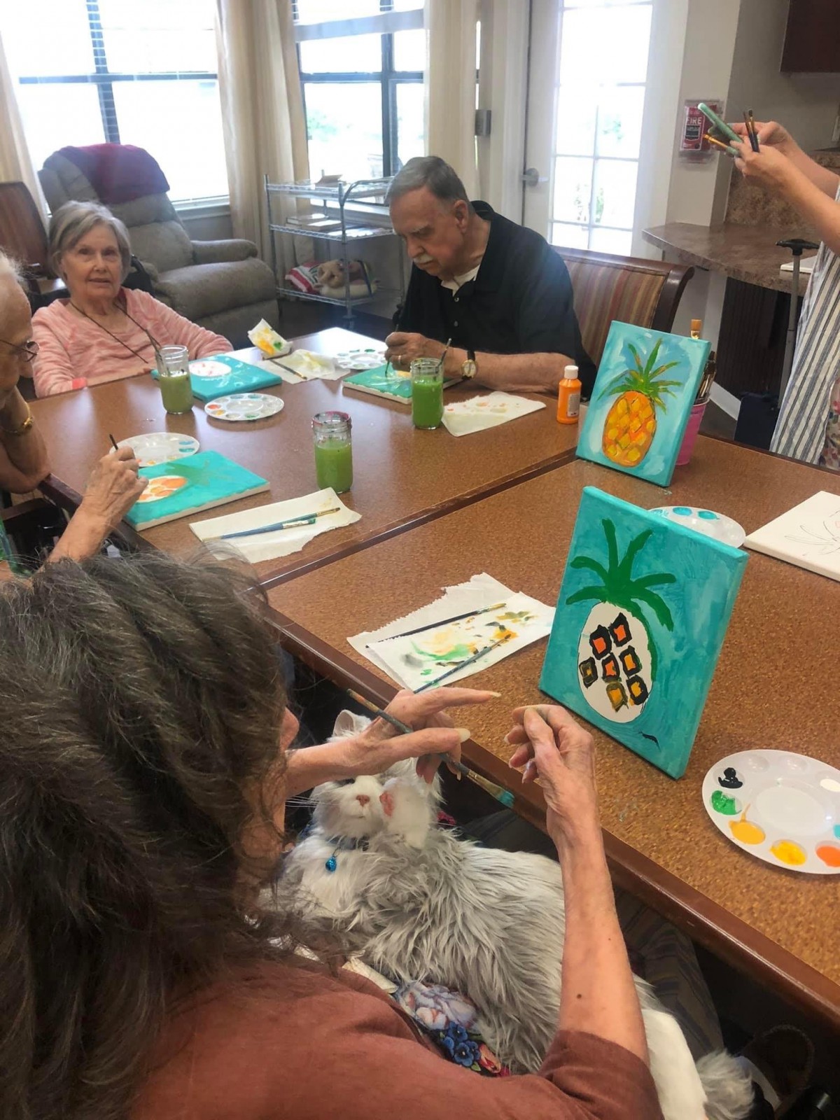 Elderly individuals participate in a group painting session, creating vibrant artwork on canvas.