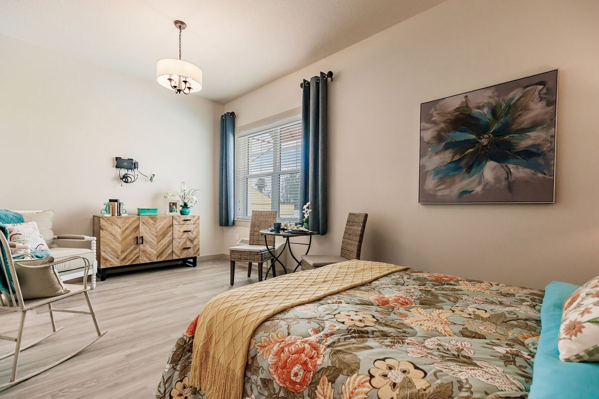 A cozy bedroom interior with floral bedding, modern furniture, and elegant decor.