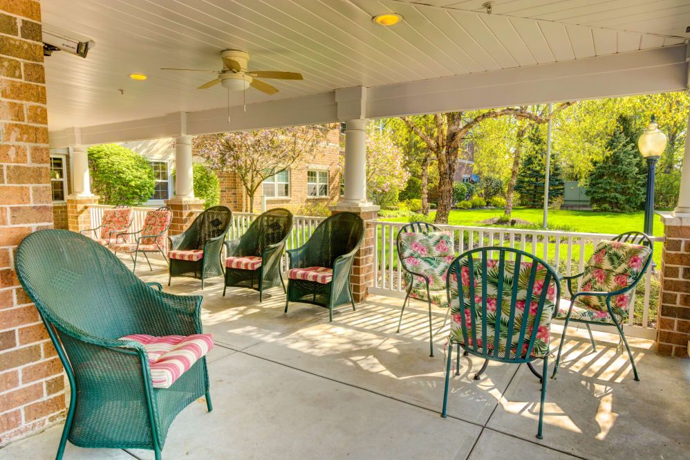 A cozy covered porch with wicker chairs and a garden view, perfect for relaxation.