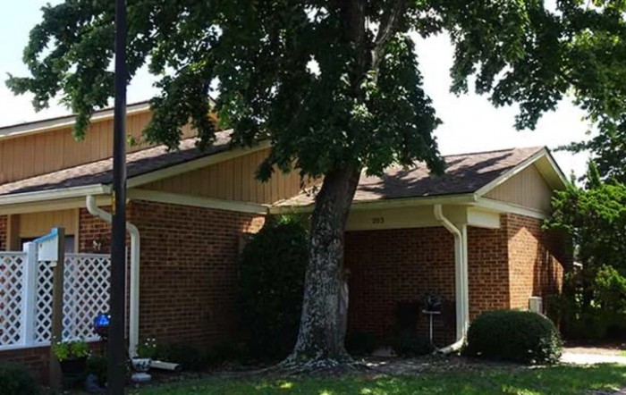 A brick house with a large tree in the front yard.