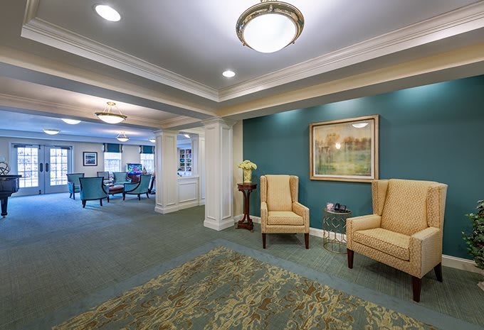 A cozy lobby area with armchairs and a decorative rug, illuminated by ceiling lights.
