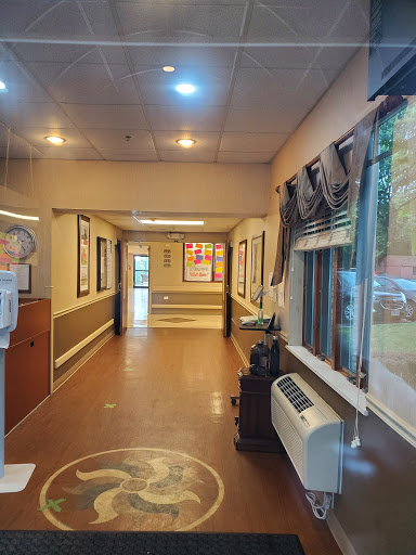 A view of a well-lit hallway adorned with artwork and featuring large windows.