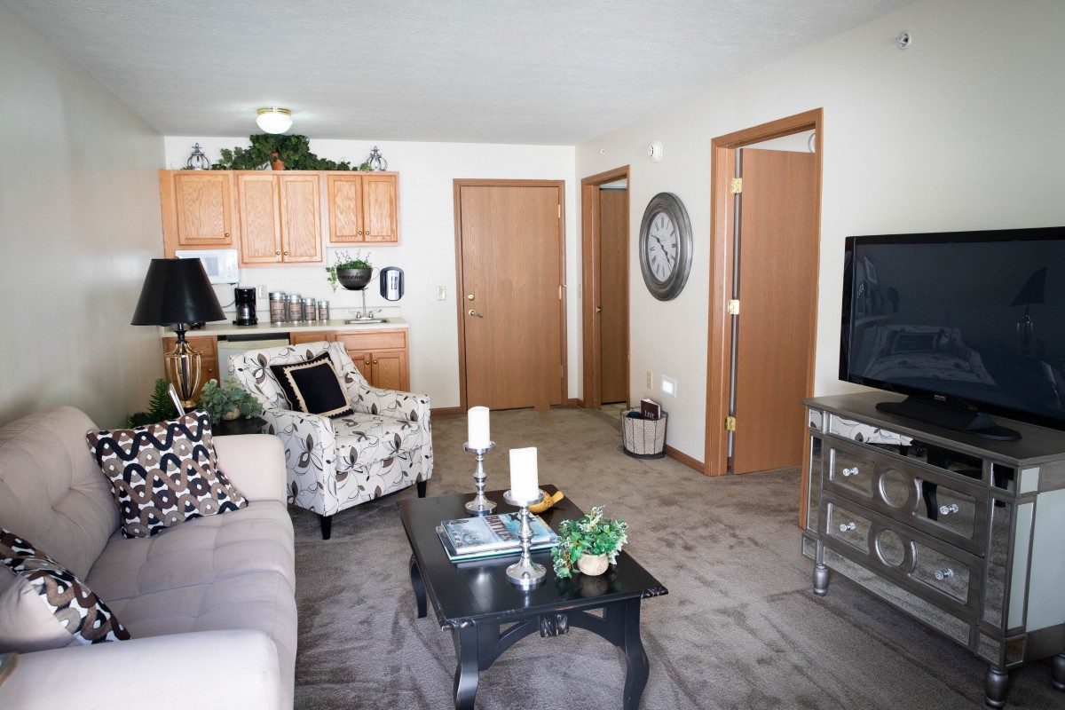A modern living room with a cozy seating area, television, and adjacent kitchen space.