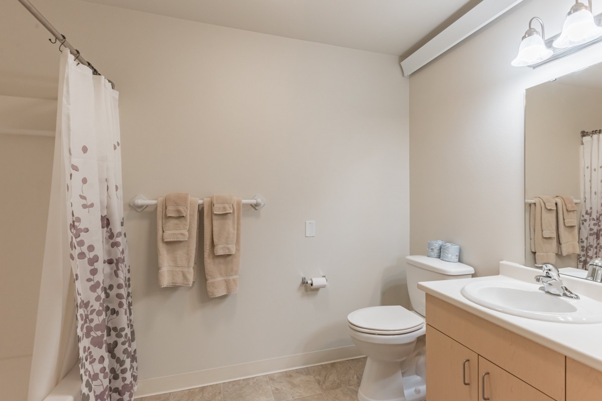 A clean and minimalist bathroom with a toilet, sink, and shower curtain.