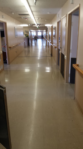 A clean, well-lit hallway in a building, featuring polished floors and doors along the sides.