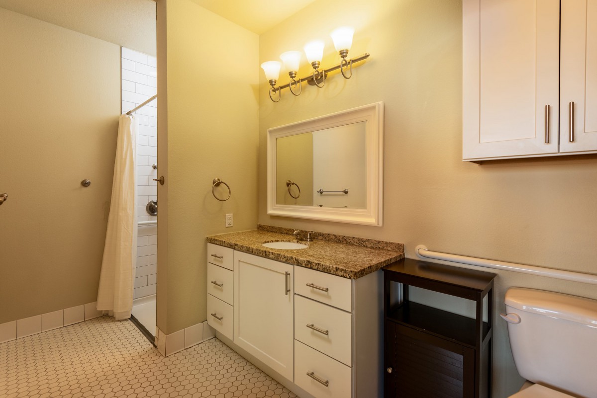 A well-lit bathroom with a sink, mirror, and cabinets.