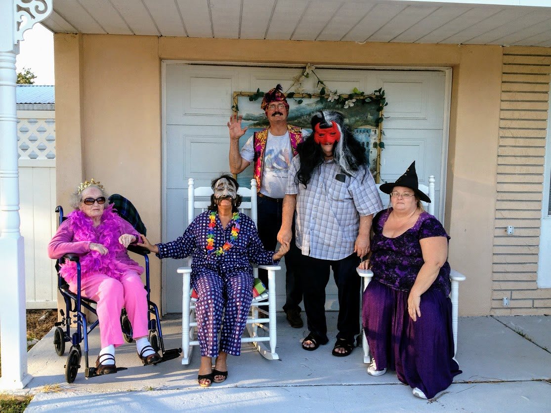 A group of people in Halloween costumes pose together outside a building.