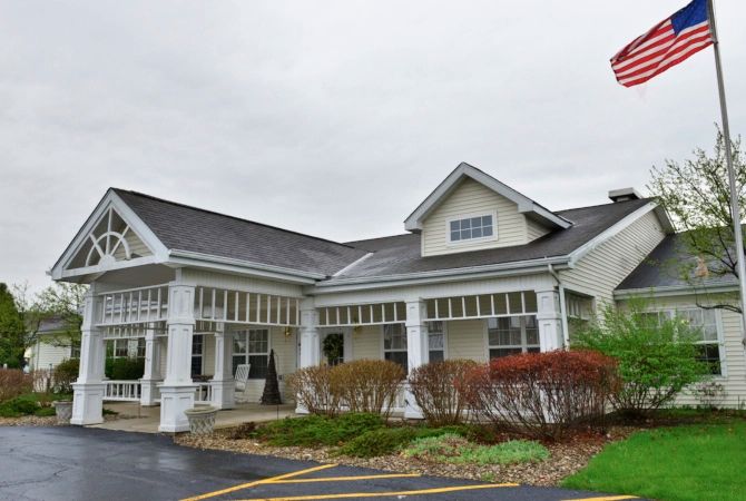 A suburban residential building with a well-maintained garden and driveway under an overcast sky.