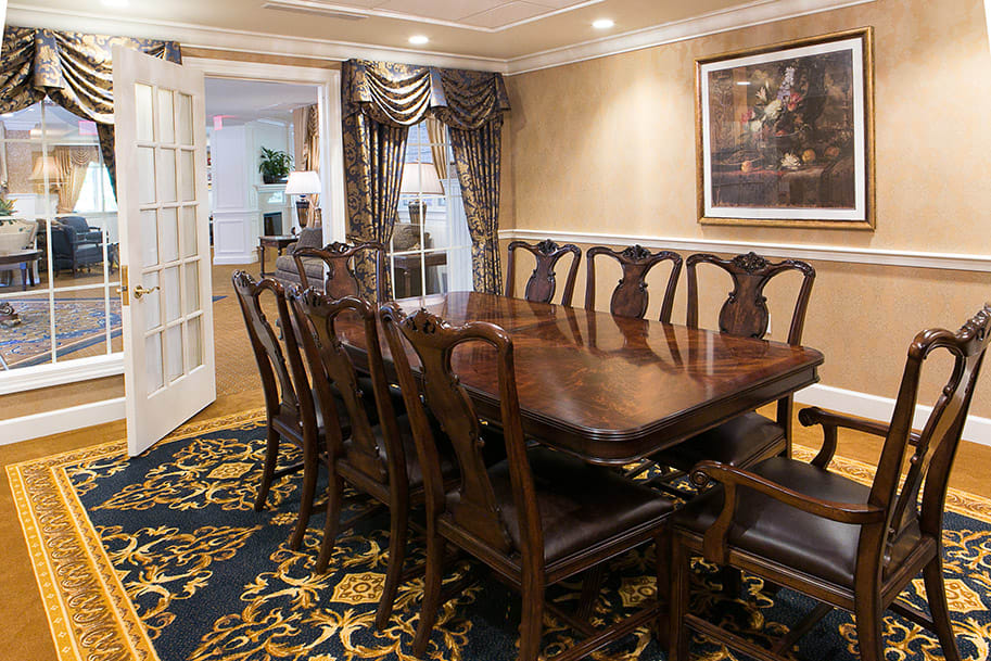 Elegant dining room with a large wooden table and chairs, featuring classic decor and artwork.