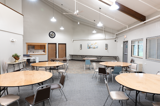 A spacious community room featuring circular tables and chairs, perfect for gatherings and events.