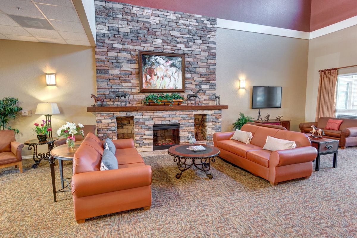 A cozy living room with a brick fireplace, two leather sofas, and a round coffee table.